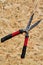 Vertical shot grass shears on plywood desk background.