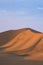 Vertical shot of a great dune in a desert illuminated by sun rays at sunset