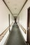 Vertical shot of the hallway of a building with white walls under the lights