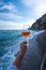 Vertical shot of a hand holding a drink on Positano Amalfi shore background in South Italy