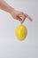 Vertical shot of a hand holding a yellow passionfruit isolated on a white background