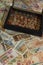 Vertical shot of a handful of numismatic collection banknotes and a wooden box with coins from various countries of the world in a