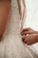 Vertical shot of hands tieing a wedding dress