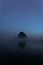 Vertical shot of a Haystack Rock outcrop in Cannon foggy Beach, Oregon at dusk