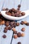 Vertical shot of a heap of black peppercorns and a white spoon on a wooden surface