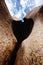 Vertical shot of a heart-shaped hole between rocks under a cloudy blue sky