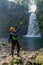 A vertical shot of a Hispanic cheerful rock climber in a helmet hat and safety harness celebrating an achievement