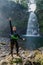 A vertical shot of a Hispanic cheerful rock climber in a helmet hat and safety harness showing a great excitement and happiness