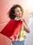 Vertical shot of a Hispanic female happily carrying her shopping bags