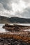 Vertical shot of the historic Isle of Skye cliff over the water under a cloudy sky in Scotland