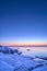 Vertical shot of an idyllic frozen rocky shore with blue and pink sunset in the background