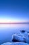 Vertical shot of an idyllic frozen rocky shore with blue and pink sunset in the background
