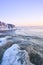 Vertical shot of an idyllic frozen rocky shore with pink sky on the horizon, perfect for wallpapers