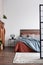 Vertical shot of industrial bedroom with hardwood floors, copper fireplace portal and wooden bed