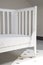 Vertical shot of an interior of a light baby room with a modern cozy whitewashed crib