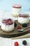 Vertical shot of jars of yogurt with jam and fresh berries on a tray