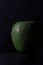 Vertical shot of a juicy apple with waterdrops isolated on a black background