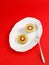 Vertical shot of kiwi fruits cut in halves in white plate on red background