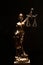 Vertical shot of lady justice bronze statue isolated on a black background