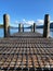 Vertical shot of a lakeside jetty with hills and blue sky in the background