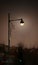 Vertical shot of a lamp with Christmas ornaments lined up with moon as lightbulb at night