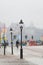 Vertical shot of lampposts on the streets of Stockholm with people passing by in the fog