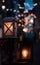 Vertical shot of lanterns with illuminated candles and bokeh lights on the background