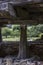 Vertical shot of a large vertical megalith supporting an old wooden house