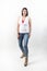 Vertical shot of a Latino female with jeans and white shirt posing with casual attitude in a studio