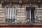 A vertical shot of le Paris sign on a building facade with two windows one opened one closed