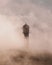 Vertical shot of a lighthouse covered by fog