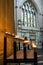 Vertical shot of the lit candles in the church on the background of the stained glass window