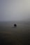 Vertical shot of a lonely squatting person taking a picture of beach isolated on foggy background