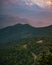 Vertical shot of lush forested mountains under a cloudy sunset sky