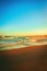 Vertical shot of a majestic clear twilight sky over a wet sandy beach and a wavy seawater