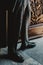 Vertical shot of a male in classic checkered trousers standing against an engraved door