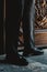 Vertical shot of a male in classic checkered trousers standing against an engraved door