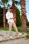 Vertical shot of a male model in sunglasses posing on background of palms