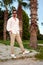 Vertical shot of a male model in sunglasses posing on background of palms