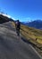 Vertical shot of a male riding a bicycle on a long road in a mountain field