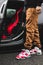 Vertical shot of a male wearing red Jordan 6 carmine sneakers with a car in the background