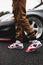 Vertical shot of a male wearing red Jordan 6 carmine sneakers with a car in the background