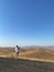 Vertical shot of a man standing and photographing the hills on a sunny day