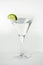 Vertical shot of a Martini glass with a twist of lime on white background