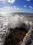 Vertical shot of the massive waves hitting the rocky shore on a sunny day