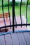 Vertical shot of the metal fence of a balcony with the view of a park in the background