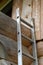 Vertical shot of a metal rusty ladder leaned on a wooden wall