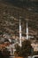Vertical shot of minarets of a mosque on a slope of a green mountain