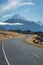 Vertical shot of the Mount Cook road in New Zealand with snowy mountains in the background