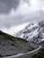 Vertical shot of a mountain pathway on grey clouds background